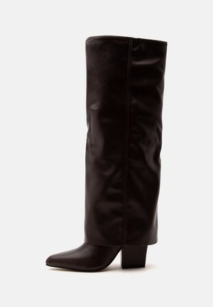 Botte haute en cuir marron foncé avec un petit talon carré et un bout pointu sur un fond uni.