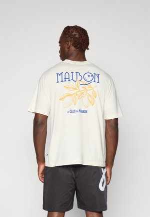 Light cream t-shirt featuring blue and yellow graphic design on the back, including text and a lemon motif. Paired with dark shorts.