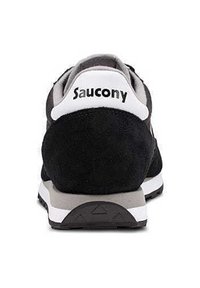 Sneaker in suede nera con accenti bianchi e grigi. Presenta un colletto imbottito e il nome del marchio "Saucony" ben visibile sul tallone.