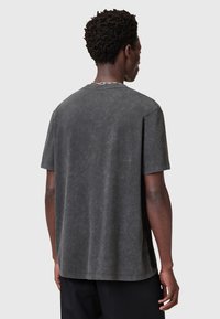 Mörkgrå oversized t-shirt gjord av mjukt, texturerat tyg. Har rund hals och korta ärmar med en avslappnad passform.