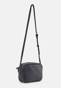 Bolso cruzado de cuero negro con un acabado texturizado, forma rectangular, cremallera dorada y una correa ajustable.