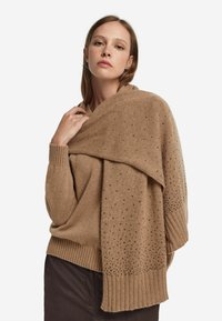 Sweter camelowy o warstwowym kroju z teksturowanymi akcentami, wyposażony w ściągacze na rękawach i asymetryczne układanie tkaniny.