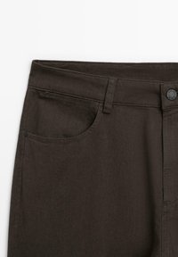 Pantaloni in denim marrone scuro con una texture liscia, un classico design a cinque tasche e una chiusura con bottone metallico in vita.
