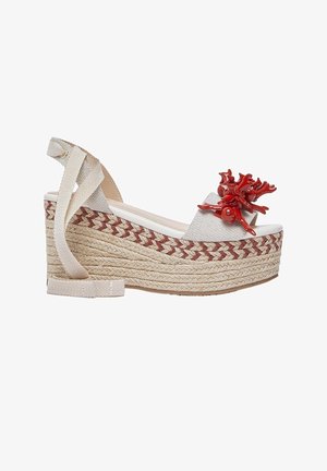 Sandalo beige con zeppa piattaforma, suola in corda intrecciata, lacci alla caviglia, cinturino bianco e decorazione a forma di corallo rosso sulla fascia anteriore.