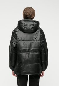 Czarna kurtka puchowa z kapturem, wykonana z gładkiego materiału przypominającego skórę. Posiada luźny krój i poziome pikowanie.