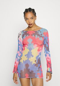 Vestido justo de manga longa em cores vibrantes com padrões abstratos de quebra-cabeça. Feito de tecido elástico, com decote barco e forma ajustada.