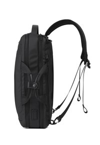 Zaino nero slim mostrato di lato con spallacci imbottiti, numerosi scomparti con zip e fibbie regolabili.