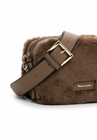 Borsa a tracolla in pelle e pelliccia sintetica marrone, con una fibbia dorata, chiusura a zip e una patch con logo. Texture morbida e forma rettangolare.
