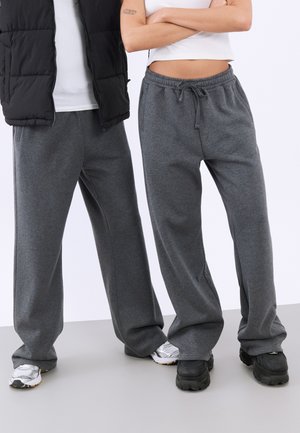 Pantaloni de trening gri cu o croială lejeră, având un talie elastică și șnur. Textură moale, potriviți pentru purtarea zilnică.