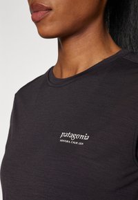 Czarny T-shirt wykonany z miękkiego materiału, z ryżowym dekoltem i białym logo "Patagonia" z napisem "Ventura, CALIF. USA" poniżej.
