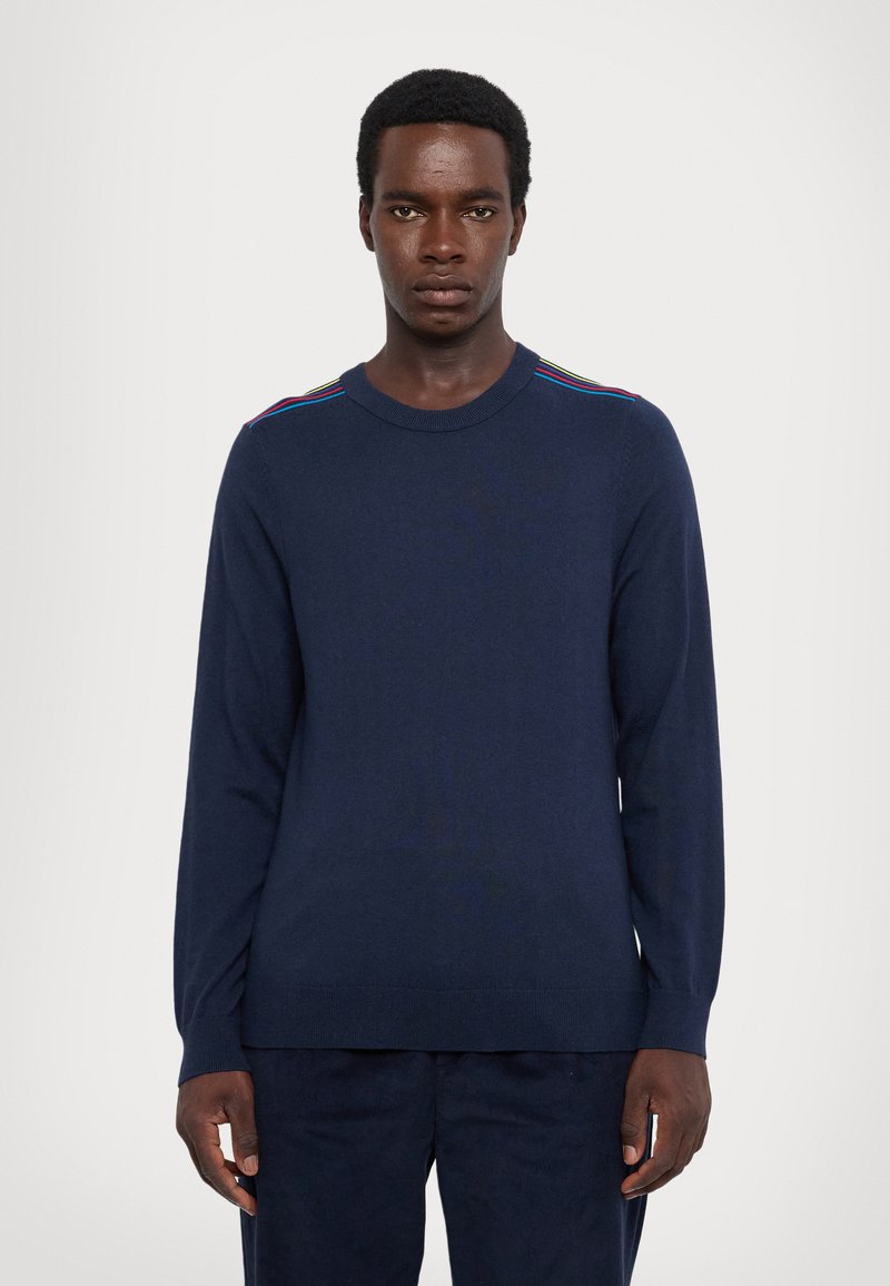 Maglione blu navy con maniche lunghe, scollatura rotonda e strisce colorate sulle spalle. Realizzato in tessuto morbido e strutturato.