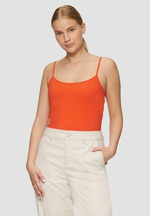 Pomarańczowy dopasowany top na ramiączkach z cienkimi paskami, zestawiony z kremowymi spodniami w kant. Top ma gładką teksturę i prosty design.