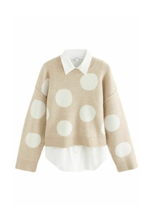 Beige pullover neulepaita, jossa on valkoisia pilkkuja, pyöreä kaula-aukko ja pitkät hihat. Vaatteen päällä valkoinen kauluspaita.