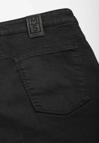 Pantalons en denim noir dotés d'une poche arrière avec un subtil détail de couture et d'une étiquette en cuir signée au niveau de la taille. Texture lisse.