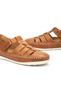 Sandalias de cuero marrón con diseño recortado, costuras blancas y hebilla ajustable. Suela de goma para agarre y comodidad.