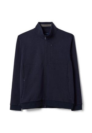 Giacca blu navy con chiusura a zip completa, collo alto e tasche con zip sul petto e sui lati, esposta su sfondo bianco.