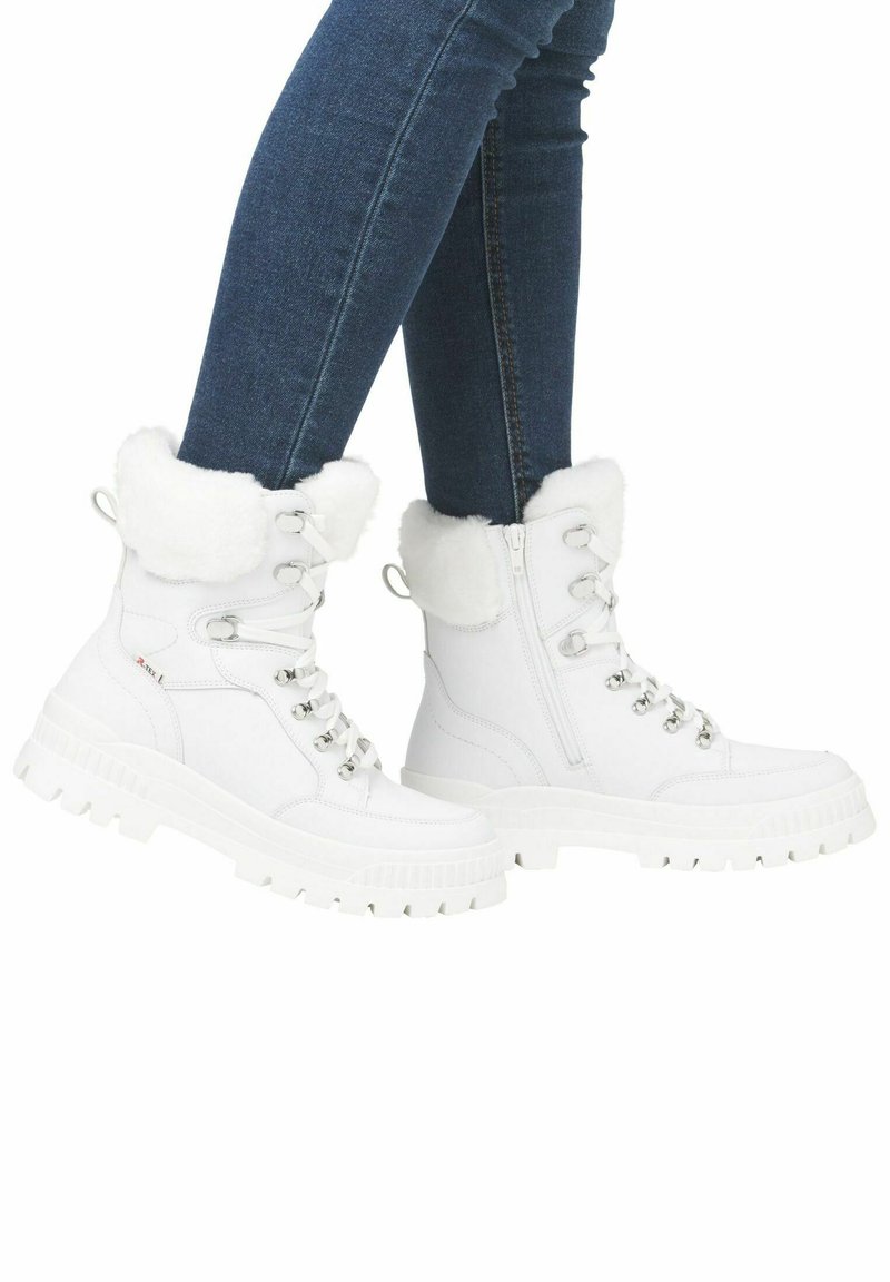 Botas de tobillo blancas con cordones, con un borde de pelaje sintético, suela de goma y detalles metálicos en plata; presentan un cierre lateral con cremallera y un material superior texturizado.