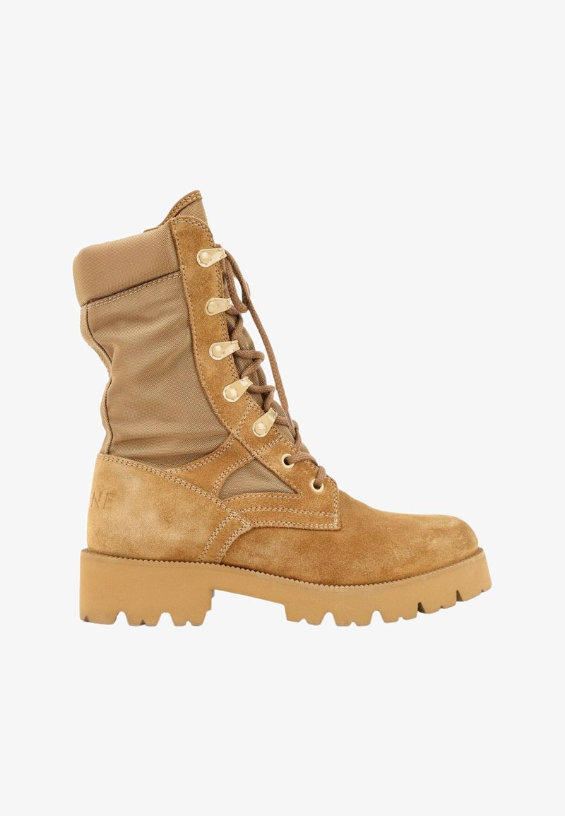 Botte style militaire en daim et tissu beige, avec semelle épaisse à crampons et col de cheville rembourré, vue de côté.