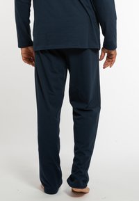 Marineblaues Loungewear-Set mit langen Ärmeln und locker sitzenden Hosen aus weichem Baumwollstoff, das eine entspannte Silhouette und ein einfaches Design aufweist.