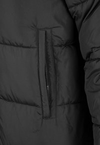 Mustamust kattega jakk, millel on külgedel vertikaalne lukuga tasku ja nähtavad õmblused.