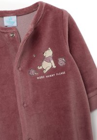 Mono de nieve para bebé en suave y texturizado forro polar rosa empolvado, con un gráfico de un oso, una bola de hilo y el texto "¡MÁS MIEL, POR FAVOR!" en blanco.