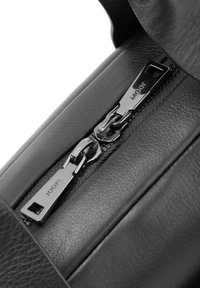 Črna usnjena ročna torba z metalik srebrnim zadrgo in detajlom logotipa. Dizajn vključuje teksturirane poudarke in elegantno obliko.