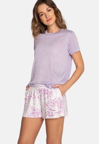 Top corto de color púrpura claro con mangas cortas, combinado con pantalones cortos blancos que presentan un patrón abstracto en rosa. Textura suave y ajuste relajado con cinturilla elástica.