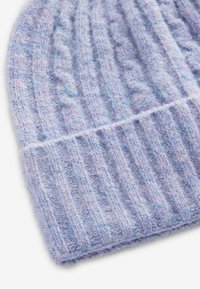 Stickad mössa i mjuk, ljuslila ullblandning. Texturerad ribbdesign med en vikbar kant i basen, som visar upp ett mysigt och varmt utseende.
