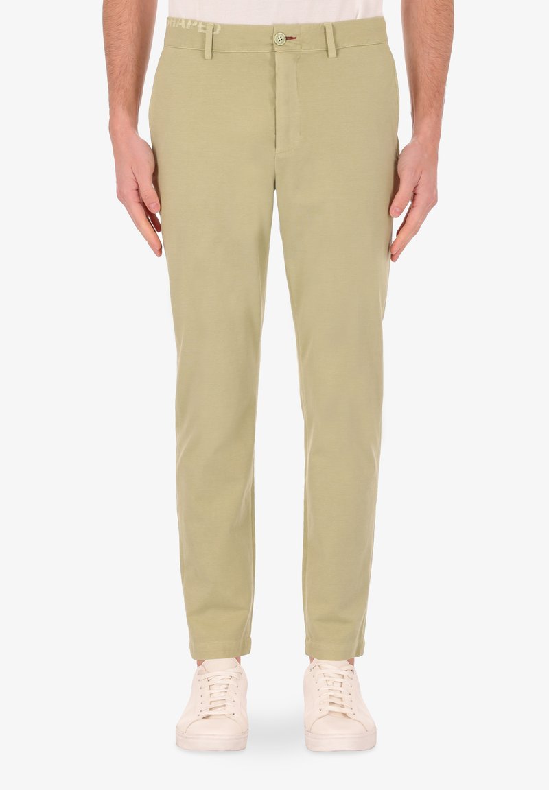Chinos in cotone verde chiaro con una vestibilità slim, chiusura con bottone e tasche laterali, abbinati a sneakers bianche con lacci.