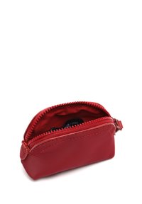 Crvena torbica na zip, napravljena od glatke najlonske tkanine, s obloženim unutrašnjim dijelom i kontrastnim šavovima. Kompaktni dizajn s zaobljenim oblikom.