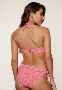 Conjunto de bikini de estampado rosa que presenta un diseño de cuello halter con lazos y un cierre rectangular en la espalda; la parte inferior tiene lazos laterales y un corte moderado.