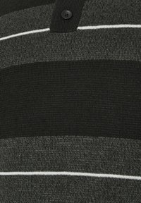Nahaufnahme eines Strickstoffs mit horizontalen dunkelgrauen, schwarzen und weißen Streifen und einem schwarzen Knopf oben in der Mitte.
