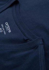 Námořnická modrá bavlněná tričko s kulatým výstřihem, krátkým rukávem a viditelnými švy. Etiketa uvádí 100 % bavlna.