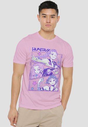 Pink cotton t-shirt featuring a graphic print of three animated characters, outlined in purple, set against the shirt's light background.