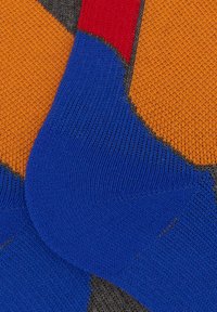 Calzini multicolori con sezioni di arancione, blu, rosso e grigio. Il tessuto presenta un motivo di maglia texturizzato su tutta la superficie.