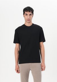 Tricou negru cu manșete scurte și guler rotund, realizat dintr-un material moale, având o textură netedă și fără logo-uri sau modele vizibile.