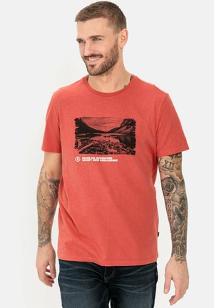 Rood T-shirt met korte mouwen, gemaakt van zachte stof, met een zwarte grafische print van een landschap en tekst, gecombineerd met een donkere spijkerbroek.
