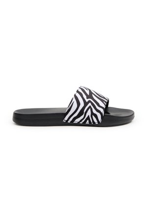 Sandalia de slide negra con una tira ancha con un patrón de rayas de cebra blancas, parte superior texturizada y una suela negra plana y suave.