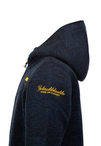 Mörkblå hoodie med en tvåtonig textur, med en gul broderad logotyp och en dragsko i huvan, visad från sidan.