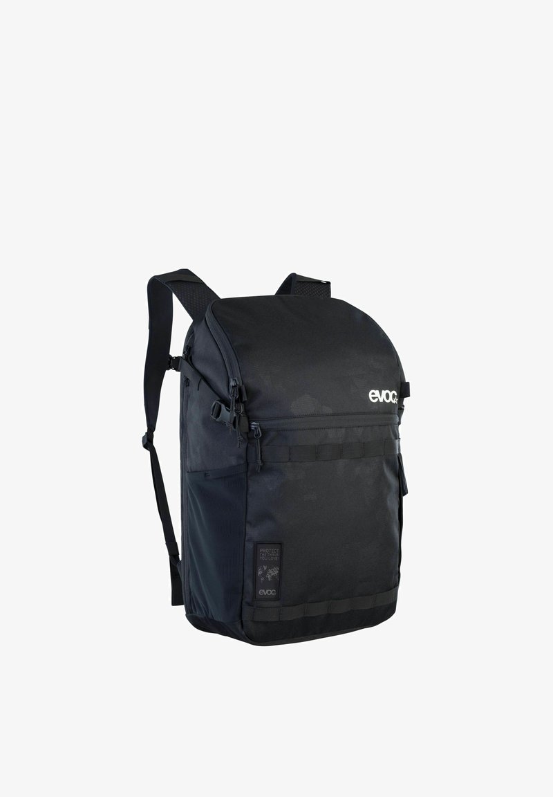 Mochila negra hecha de tela resistente, con una parte superior redondeada, un compartimento frontal con cremalleras, correas ajustables y base reforzada.