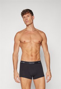 Fekete pamut boxer alsónadrág puha derékkal, amelyen a Calvin Klein logó található. Az anyag simának és rugalmasnak tűnik.