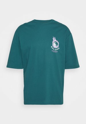 Türkisfarbenes T-Shirt mit kurzen Ärmeln, kleinem flammenden Yin-Yang-Symbol und dem Schriftzug "BALANCE" auf der oberen linken Brust.