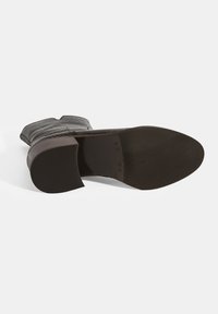 Braune Lederstiefel mit strukturierter Optik, abgerundeter Spitze und niedrigem Blockabsatz, ausgestattet mit einer glatten Gummisohle und dekorativen Nähten.