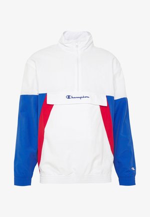Veste à enfiler Champion bicolore blanc, bleu et rouge, avec demi-fermeture éclair et logo sur le rabat de la poche avant et sur le poignet de la manche gauche.