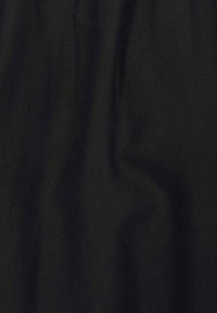 Černá bavlněná tkanina s hladkým povrchem, vykazující jemné vlny a záhyby. Žádné viditelné vzory ani kovové detaily.