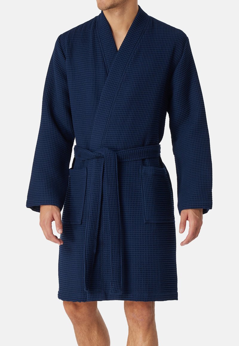 Accappatoio waffle di colore blu navy con maniche lunghe, una cintura e due tasche frontali. Presenta un colletto sciallato e un design fino al ginocchio.