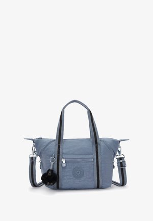 Niebieska torba materiałowa z podwójnymi czarnymi paskami na ramię, zamykaną kieszonką, okrągłym logo i przywieszką w kształcie czarnej pomponu.