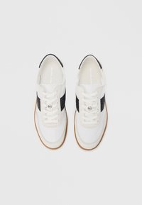 Valged ja mustad tossud paelakinnisega, millel on seemisnahalaadne must triip ja keelega ümmargune hõbedane aktsent. Põhjaks kummine pruunikaskollane tall.