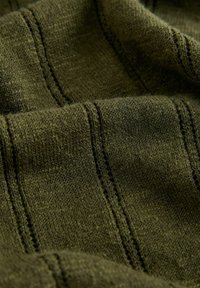 Tissu tricoté vert foncé avec des motifs de rayures verticales texturées, montrant des plis doux et des coutures détaillées.