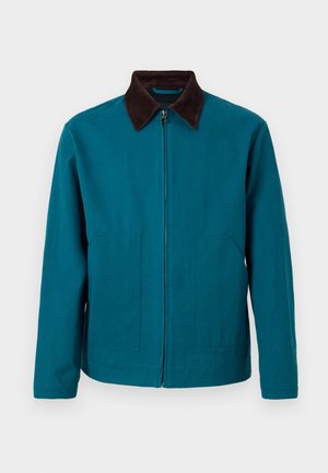 Τζάκετ με φερμουάρ σε τιρκουάζ χρώμα, με σκούρο καφέ γιακά, μακριά μανίκια και δύο μπροστινές τσέπες, παρουσιάζεται πάνω σε απλό ανοιχτό φόντο.